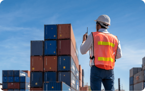 A man looking at a big mountain of containers talking into a radio device