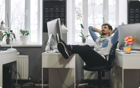 man sitting at his desk with legs up on the table relaxing and happy